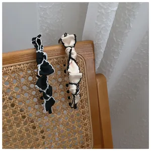 Detailed close-up of French vintage bow headbands in black and beige on a woven chair