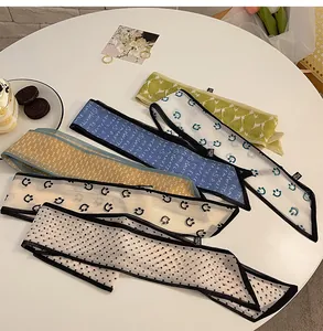 Flat lay of diverse floral and polka dot silk scarves on a white table with lifestyle decor