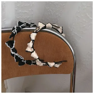 Detail of vintage French style bow headbands in black and cream with wavy embroidery