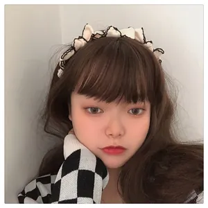 Close-up of cream pleated headband with black contrast stitching edge on a female model
