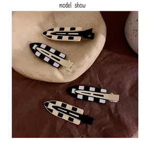 Detailed macro view of four checkerboard pattern hair clips in black and white finish