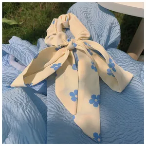 Detailansicht des cremefarbenen Schleifen-Haargummis mit blauem Blumenmuster aus Chiffon