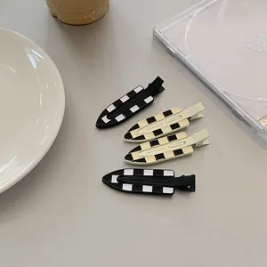 Detail view of black and white checkered hair clips on a stylish ceramic plate