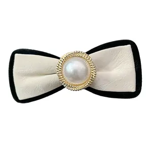 Elegant white leather bow hair clip with black velvet trim and center pearl detail