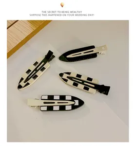 Detail of four checkerboard pattern hair clips with black and white enamel finish