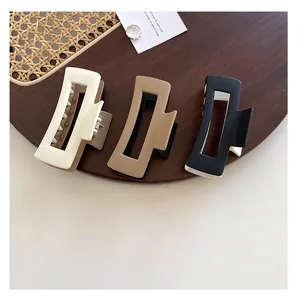Three-pack matte square hair claw clips in cream, coffee, and black on a wooden tray