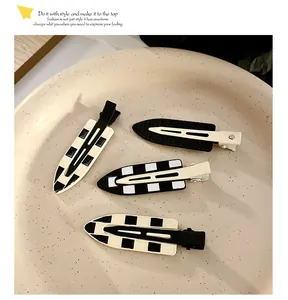 Detailed set of four black and white checkered hair clips on a ceramic plate