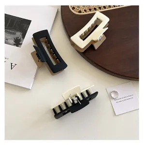 Three matte rectangular hair claws in black, beige, and bicolor on a modern set
