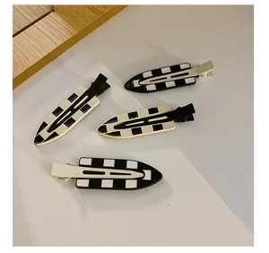 Close-up of four checkerboard hair clips showing metal duckbill base and resin surface