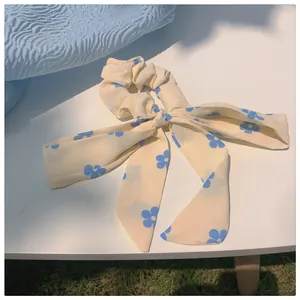 Nahaufnahme des cremefarbenen Haargummis mit blauem Blumenmuster und eleganter Schleife