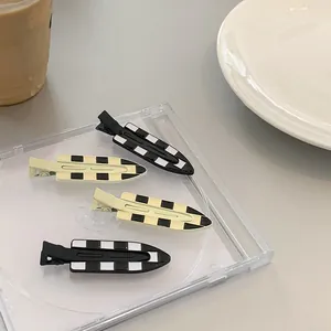 Set of four checkerboard seamless hair clips in black and white on a ceramic plate