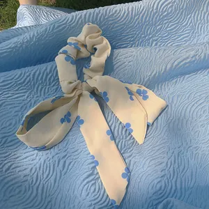 Eleganter cremefarbener Haargummi mit blauen Blumen und langem fließendem Band