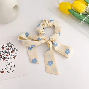 Elegant light yellow bow scrunchie with blue flower pattern on white tabletop