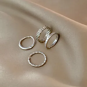 Set di anelli d'argento minimalisti con texture intrecciate e lucide su seta elegante