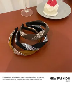 Close-up of twist headbands with houndstooth and solid fabric textures on a wooden table