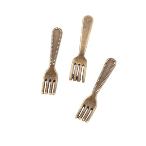 Detail view of vintage bronze-style fork charms for DIY jewelry and crafts