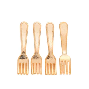 Close-up of four golden vintage zinc alloy forks with embossed dotted handle details