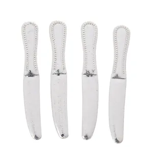 Close-up of four vintage silver zinc alloy knives with embossed beaded handles on white background