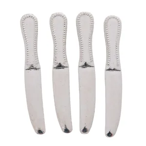 Macro detail of four silver-colored miniature dining knives with beaded edge relief carving