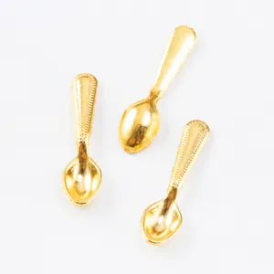 Detailed macro view of three miniature gold zinc alloy spoons with textured handles for DIY