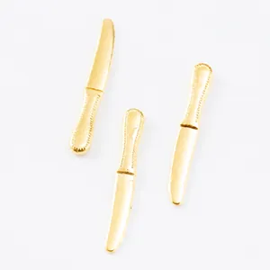 Macro detail of three golden miniature butter knife charms with bead-edge decorative patterns