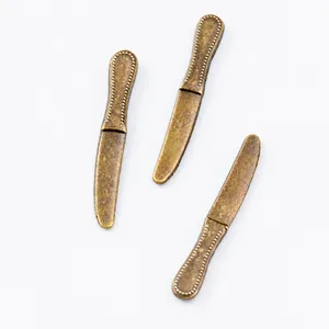 Macro shot of vintage zinc alloy cutlery charms with detailed bead patterns for DIY jewelry