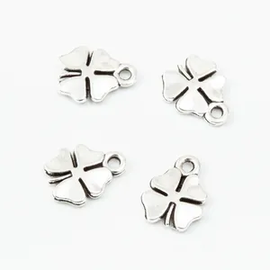 Detailed macro view of four vintage silver alloy four-leaf clover charms with textured finish