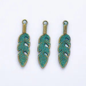 Detailed view of vintage bronze feather pendants with teal blue enamel finish and hole
