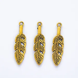 Detailed view of three vintage gold leaf feather charms for DIY jewelry making