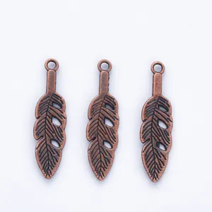 Detailed view of three vintage copper feather charms with realistic leaf textures for DIY