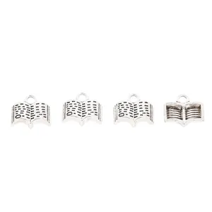 Detailed macro view of four vintage silver zinc alloy open book charms for DIY jewelry making