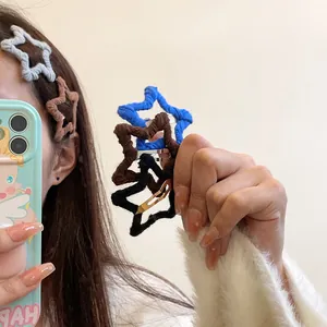 Star-shaped knitted wool hair clips in various autumn colors shown on model and held in hand