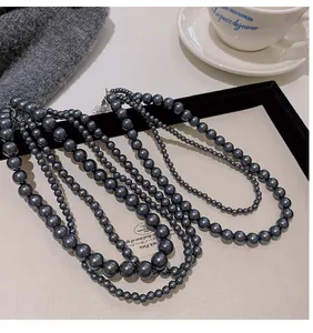 Dettaglio di una collana di perle grigio metallizzato multistrato su maglia grigia