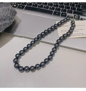 Vista dettagliata della collana di perle grigio scuro con chiusura a moschettone