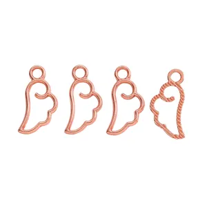 Detail of four rose gold alloy angel wing pendants with hollow-out design for DIY jewelry