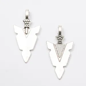 Détail macro de pendentifs flèches en alliage rétro avec texture tissée et fini métallique