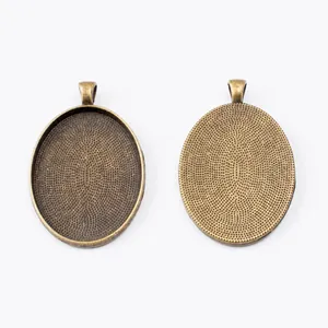 Detail view of oval antique bronze pendant base with textured back for DIY jewelry