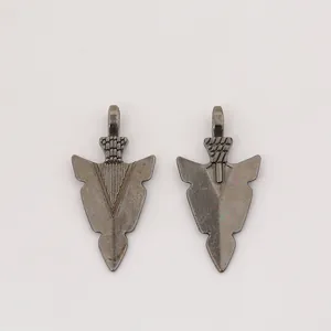 Détail macro de deux pendentifs flèche en alliage vintage avec finition gris foncé