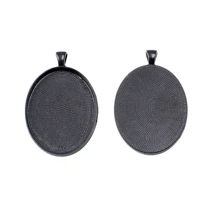 Pair of black oval alloy pendant bases with smooth front groove and textured back side