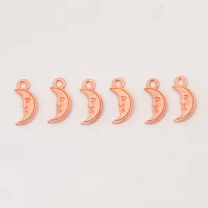 Detailed view of six rose gold crescent moon charms with vintage smiling face engravings