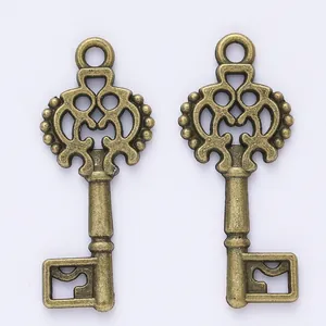 Pair of vintage bronze alloy key pendants with ornate hollow carvings on white background