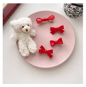 Set of four red vintage bow hair clips and a cute plush bear accessory on a display plate