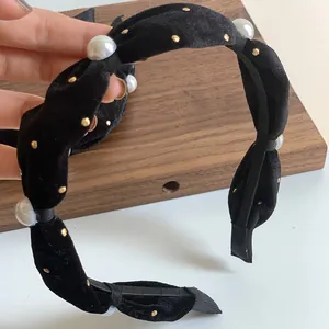 Close-up of vintage black velvet headband with elegant pearls and golden studs detailing