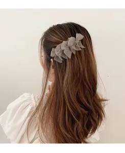 Dettaglio di tre fiocchi in organza color talpa su un fermaglio per capelli per acconciature