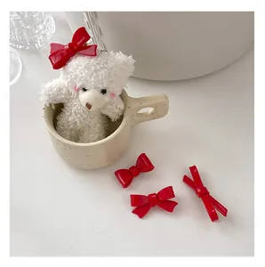 Close-up of red ribbon bow hair clips with glossy finish next to a white teddy bear