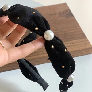 Close-up of black velvet headband with pearls, gold studs, and twisted knot detail