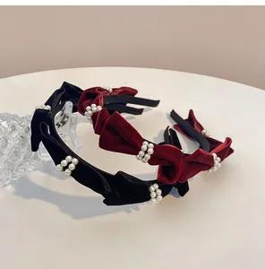 Close-up of velvet bow headbands with pearl clusters in black and burgundy red