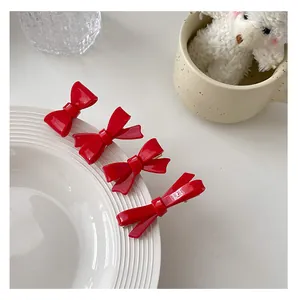 Detailed view of four red bow hair clips on a ceramic plate edge in a lifestyle setting