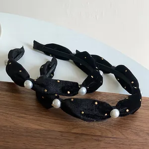 Detail of vintage black velvet headbands with pearls and gold accents on a wooden tray