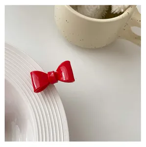 Detail shot of a glossy red bow hair clip on the edge of a ceramic plate